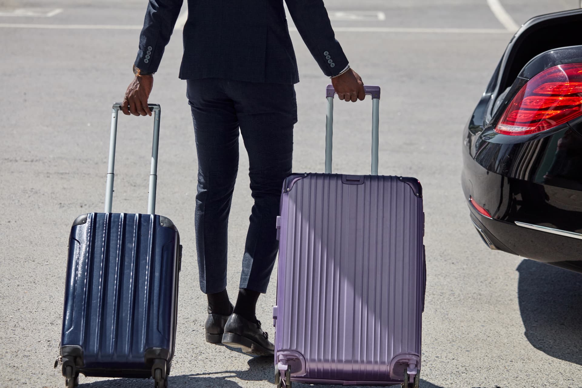 Chauffeur mit Gepäck neben einer schwarzen Limousine, Ankunft für einen Transfer